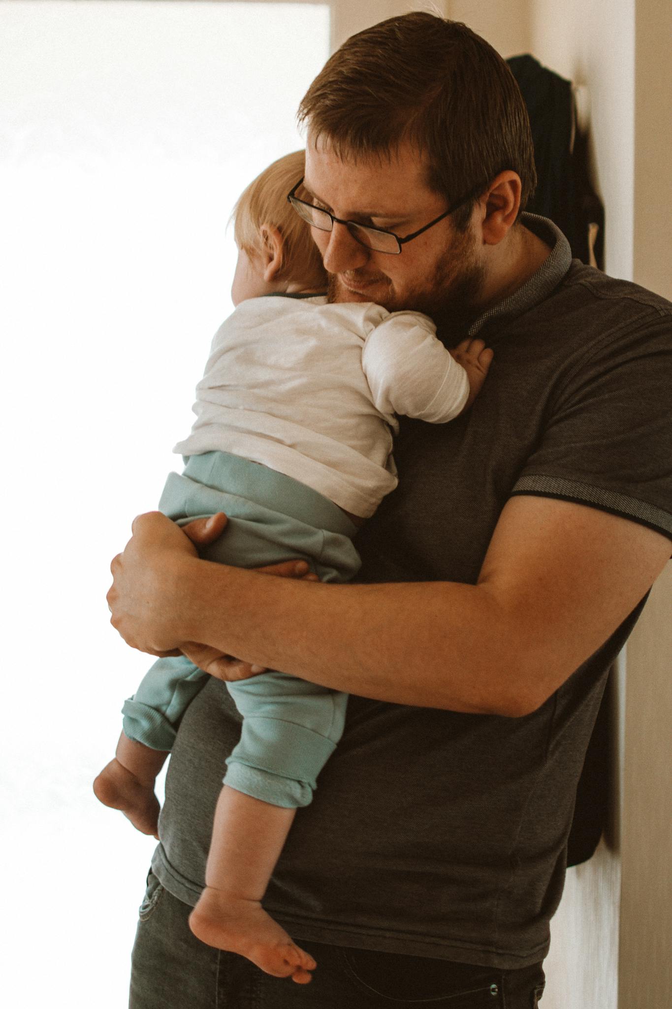 A father lovingly embraces his child indoors, showcasing parental affection and warmth.