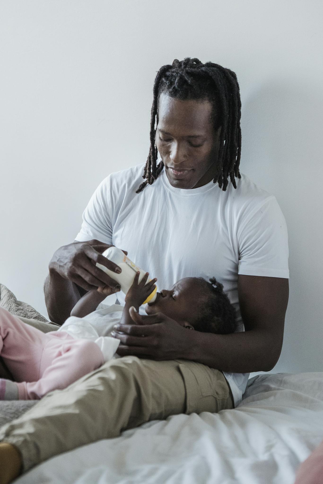 A loving father feeds his baby daughter with a bottle, highlighting their bond and warmth.